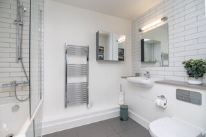 A modern bathroom with a glass-enclosed shower, a towel rack, a sink, and a mirror. - Stylish 2-bed Apartment in Southwark (London)