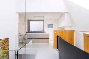 Eine moderne Küche mit großem Fenster, einem Essbereich mit Stühlen und einem Holzkasten.