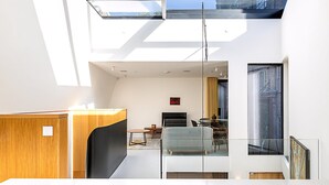 Un intérieur moderne agrémenté d’une verrière, d’un coin repas et d’œuvres d’art aux murs.
