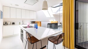 Une cuisine moderne avec des meubles blancs, un îlot central et un coin repas avec des chaises.