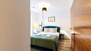 Una camera da letto con un letto, un comodino, una lampada e un quadro appeso al muro.