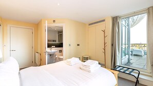 Habitació d'hotel amb un llit, un bany, una finestra amb vistes i un balcó.