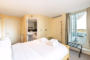 A hotel room with a bed, a bathroom, a window with a view, and a balcony. - Riverside Luxury With Iconic Views (London)