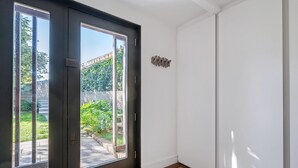 A room with a sliding glass door to a garden, a doormat, and a wall-mounted light switch. - Stylish Family Retreat in Trendy Hackney (London)