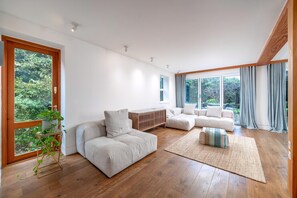 A modern living room with a sofa, a coffee table, a rug, and a plant stand. - Stylish Family Retreat in Trendy Hackney (London)
