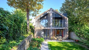 A modern house with a glass facade, a stone pathway, and a grassy yard. - Stylish Family Retreat in Trendy Hackney (London)