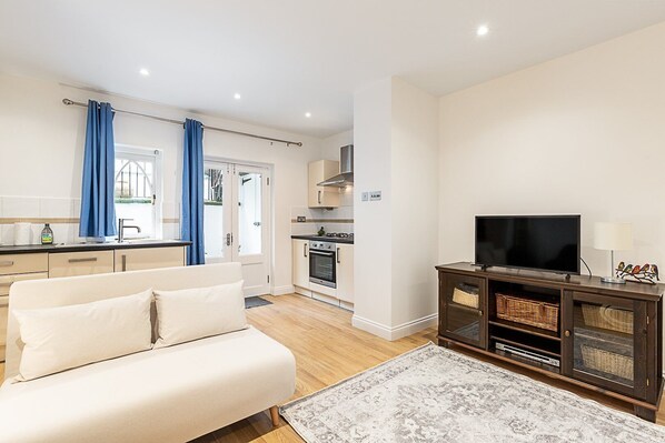 A modern living room with a sofa, TV, and entertainment unit. - Chelsea Riverside Modern Escape (London)