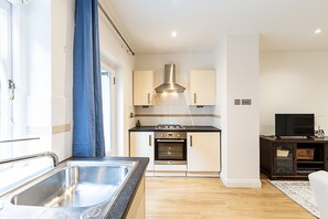 A compact kitchen with a sink, stove, oven, and cabinets. - Chelsea Riverside Modern Escape (London)