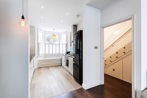 Eine moderne Küche mit einem schwarzen Kühlschrank, weißen Schränken und Holzboden.