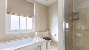 A bathroom with a bathtub, toilet, and glass shower enclosure. - Stylish Chelsea Escape With Charm (London)