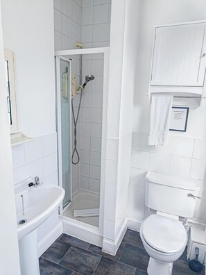 Ein Badezimmer mit Dusche, Waschbecken, Toilette und einem gerahmten Schild an der Wand.