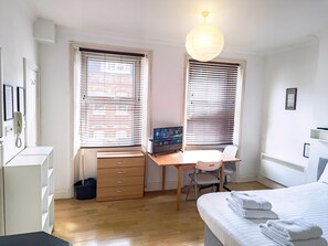 Ein Schlafzimmer mit einem Bett, einem Schreibtisch, einem Stuhl und einem Computer.