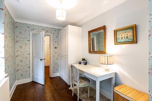 A hallway with a white door, a desk with a lamp, and two framed pictures on the wall. - Elegant English Retreat Near Maida Vale (London)