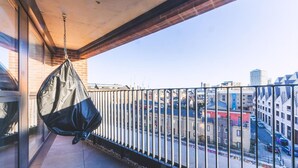 A balcony with a hanging bag, a view of a cityscape, and a building with a brick facade. - Large Bright Canal 1-bed With Balcony (London)