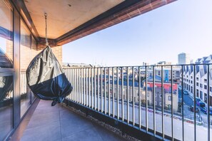 A balcony with a hanging bag, a view of a cityscape, and a building with a brick facade. - Large Bright Canal 1-bed With Balcony (London)