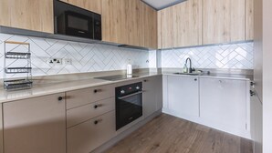 A modern kitchen with wooden cabinets, a Bosch microwave, a built-in oven, and a herringbone-patterned backsplash. - Large Bright Canal 1-bed With Balcony (London)