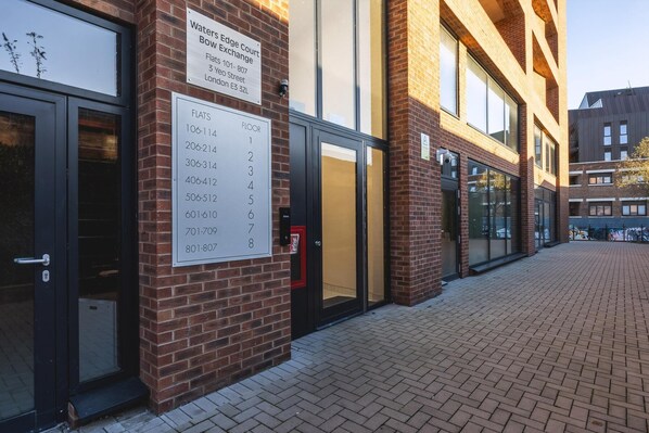 A brick building with a sign indicating the location of Waters Edge Court Exchange, including a floor number sign. - Large Bright Canal 1-bed With Balcony (London)