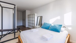 A modern bedroom with a bed, a workout station, a large mirror, and a storage unit. - Large Bright Canal 1-bed With Balcony (London)