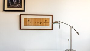 A desk with a framed poem on the wall, a desk lamp, and a framed picture above the lamp. - Bright Bold Hackney Escape (London)