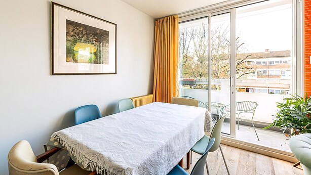 A dining area with a table, chairs, a framed picture, and a view through a large window. - Bright Bold Hackney Escape (London)