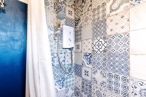 A bathroom with a shower, tiled walls, and a blue door. - Bright Bold Hackney Escape (London)