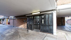 A covered entrance with a metal gate, a brick wall, and a tiled floor. - Bright Bold Hackney Escape (London)