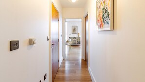 A hallway with a wooden floor, a light fixture, a door, and a framed artwork on the wall. - wba Contemporary Parkside Retreat (London)