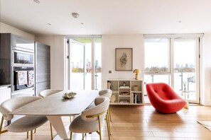 A modern kitchen with a dining area, a red chair, and a city view. - wba Contemporary Parkside Retreat (London)