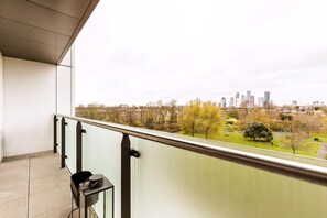 A balcony with a city view, a trash bin, and a railing. - Contemporary Parkside Retreat (London)