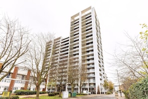 A multi-story residential building with balconies, a parking area, and a street view. - Contemporary Parkside Retreat (London)
