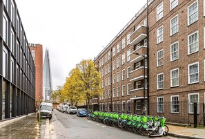 Eine Straße gesäumt von abgestellten Fahrrädern, ein Backsteinhaus und ein modernes Glasgebäude.