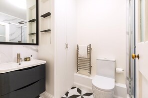 A bathroom with a white sink, dark cabinet, toilet, and a towel rack. - Modern London Bridge Retreat (London)