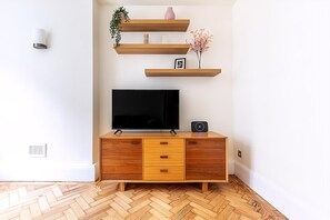 Ein modernes Wohnzimmer mit Flachbildfernseher, Holzböden und einem Fischgrätenparkett.