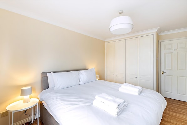 A hotel room with a bed, bedside lamp, wardrobe, and a door. - Bright Canada Water Waterside Retreat (London)