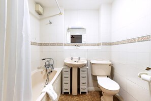 Ein Badezimmer mit Badewanne, Waschbecken, Toilette und einem Spiegel über dem Waschbecken.