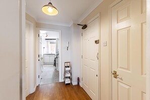 A hallway with a wooden floor, white doors, and a ceiling light fixture. - Bright Canada Water Waterside Retreat (London)