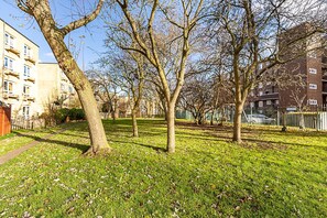 A park with trees, grass, and apartment buildings in the background. - Bright Stylish Kentish Town Retreat (London)