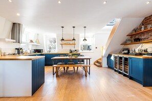 Eine moderne Küche mit einer zentralen Kochinsel, Holzböden und blauen Schränken.