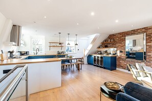 A modern kitchen with a central island, a dining area, and a loft bedroom with a view. - Stylish Notting Hill Apartment With Roof Terrace (London)