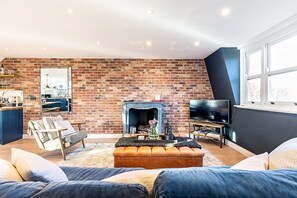 A living room with a brick wall, a fireplace, a sofa, a television, and a window. - Stylish Notting Hill Apartment With Roof Terrace (London)