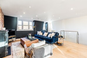 Ein modernes Wohnzimmer mit einem blauen Sofa, einem Couchtisch und einem Kamin.