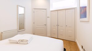 Un dormitorio con cama, radiador, puerta y armario.