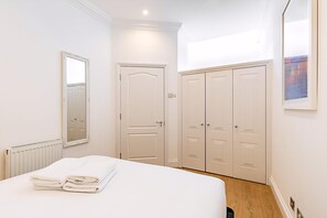 Ein Schlafzimmer mit Bett, Heizkörper, Tür und Kleiderschrank.