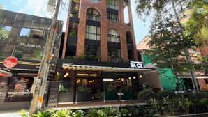 A multi-story building with a brick facade, a restaurant named 'BACU' on the ground floor, and a sign for 'Planetaws' to the left.