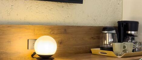 A wooden counter with a spherical light fixture, a coffee maker, and a tray with two cups.
