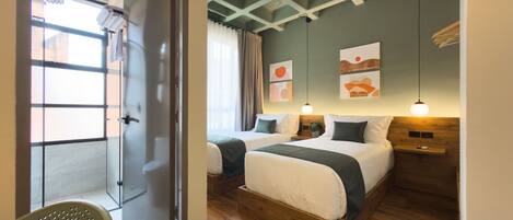 Habitación de hotel con dos camas, suelo de madera, puerta de cristal y vistas al exterior.