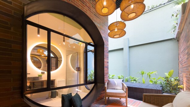 A modern interior with a circular window, a seating area with a cushioned bench, and a small table.