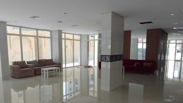 Un vestíbulo amplio con ventanas grandes, un sofá rojo y una mesa de centro blanca.