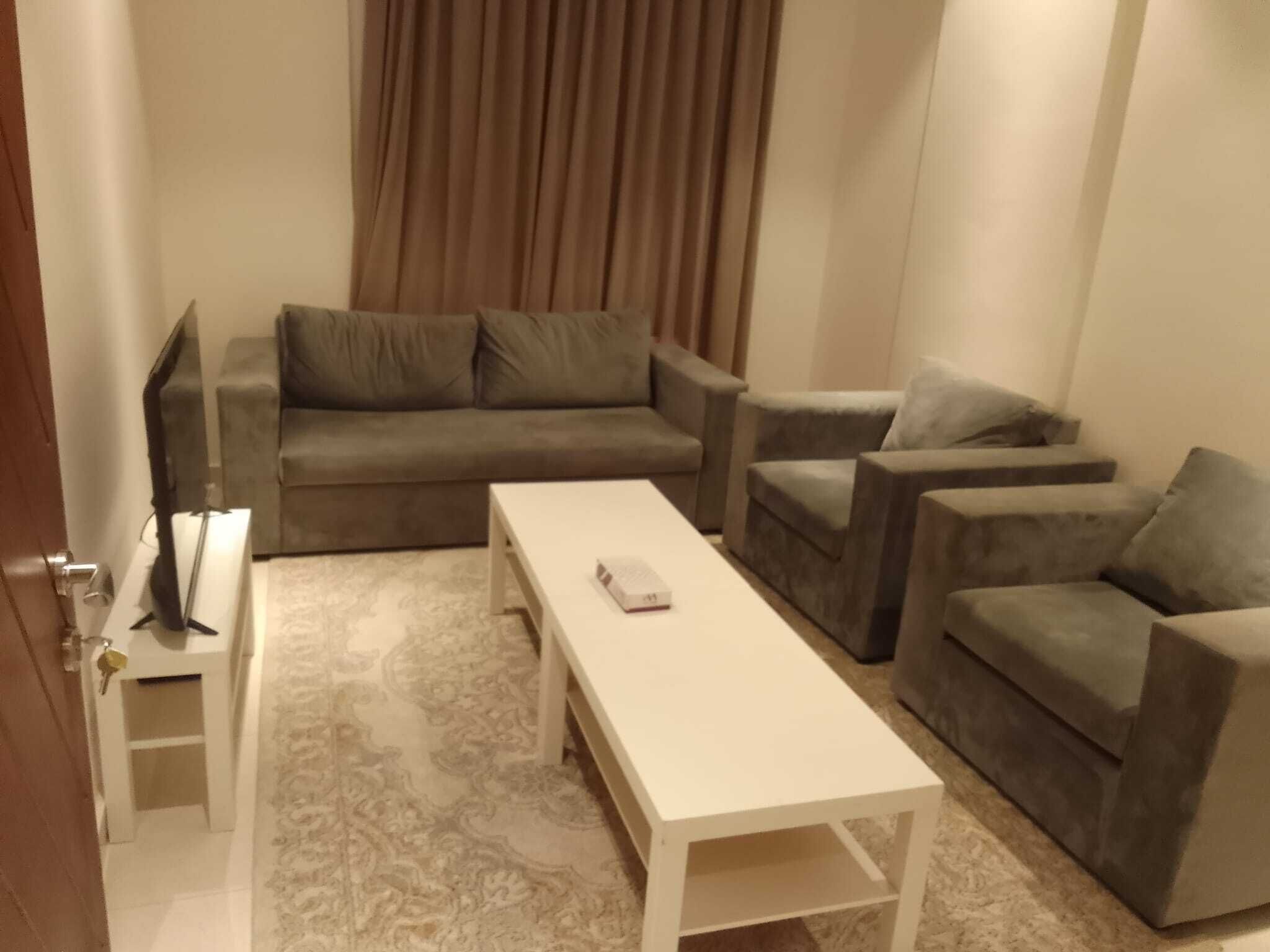 Una sala de estar con un sofá, dos sillones, una mesa de centro y un televisor.