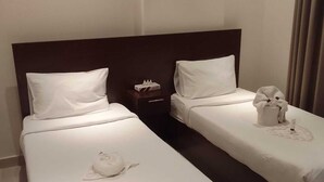 Una habitación de hotel con dos camas, una mesita de noche y un baño.